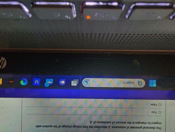 The image shows a part of a computer screen with the taskbar displaying several application icons such as Microsoft Edge, Dropbox, and possibly others, along with a search bar.

Below this, there is partial text from what appears to be a multiple-choice question or statement, with "True" and "False" options. The visible text reads:

"The chemical potential of a substance A describes a free energy change of the system with respect to changes in the amount of substance of A."

The context suggests this might be related to chemistry or thermodynamics, discussing concepts like chemical potential and free energy. There are no graphs or diagrams visible in the provided section of the image.