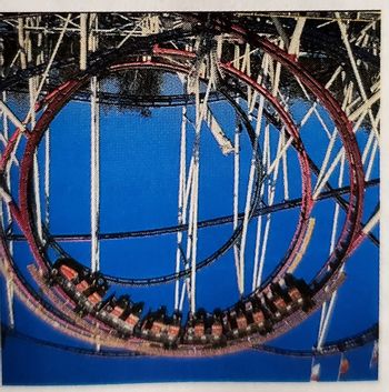 This image depicts a roller coaster loop, showcasing a train of cars as they navigate the curve of the track. The scene captures the thrill and dynamics of a roller coaster ride, emphasizing the circular motion and the gravitational forces acting on the ride and its passengers.

The roller coaster track is set against a clear blue sky, with a large loop in the foreground. The cars are shown at the bottom of the loop, illustrating the concept of centripetal force that keeps the cars secured to the track even when upside down. The structure is supported by a complex grid of beams, providing the necessary support and stability for the ride.

This visual can be used to explore topics such as physics principles in amusement park rides, including centripetal force, inertia, and the conversion of potential energy to kinetic energy. It serves as an engaging example for students learning about these scientific concepts in a real-world context.